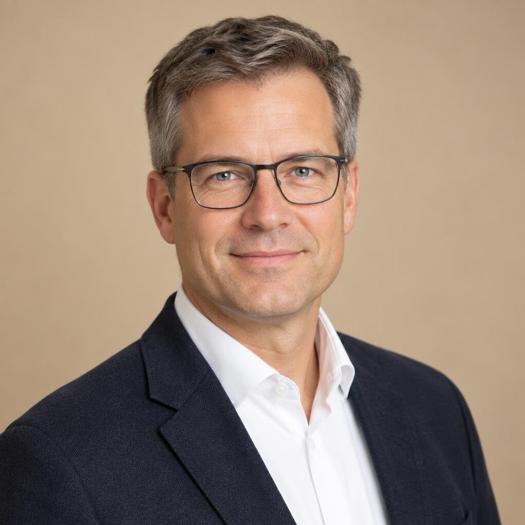 German male researcher in his forties with glasses and a blazer